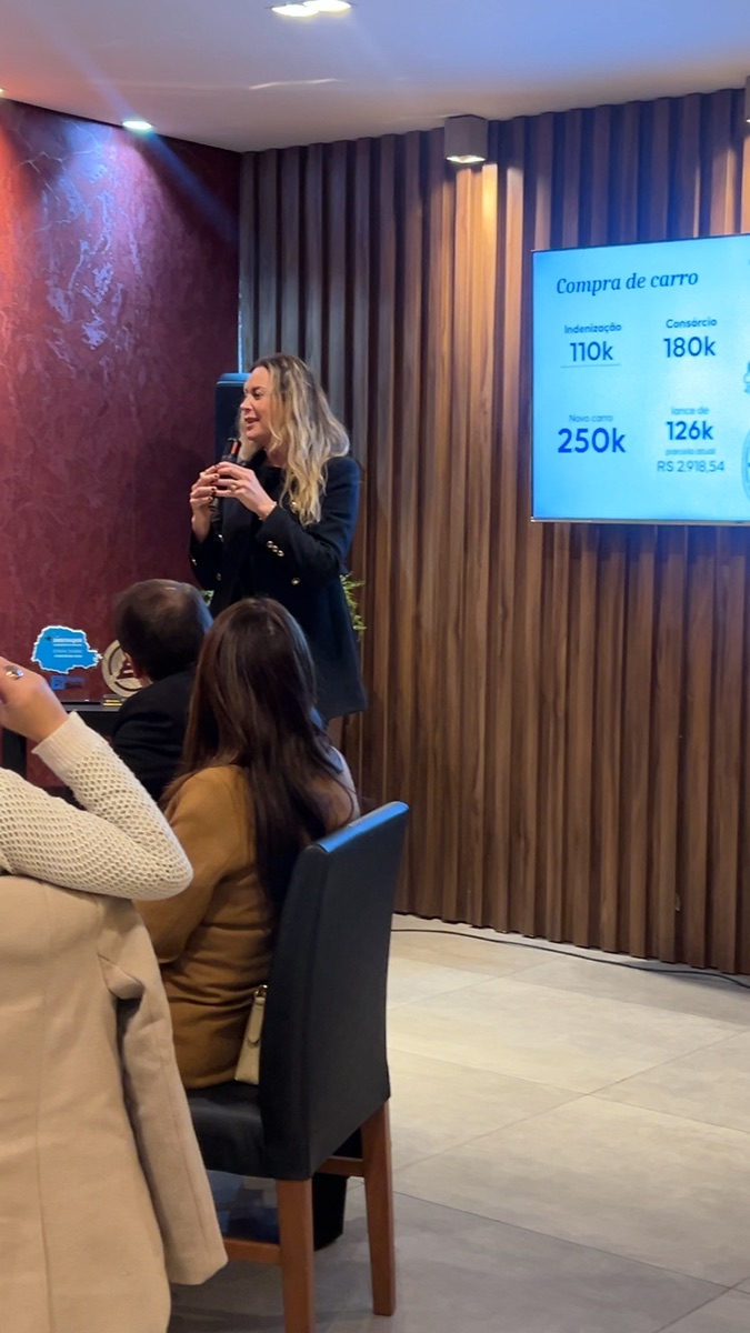 Simulação de consórcio apresentada no telão durante evento de vendas de corretora em Curitiba
